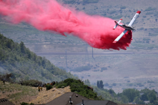 A single-engine air attack plane makes a retardant drop on a brush fire burning near homes in Draper, Utah